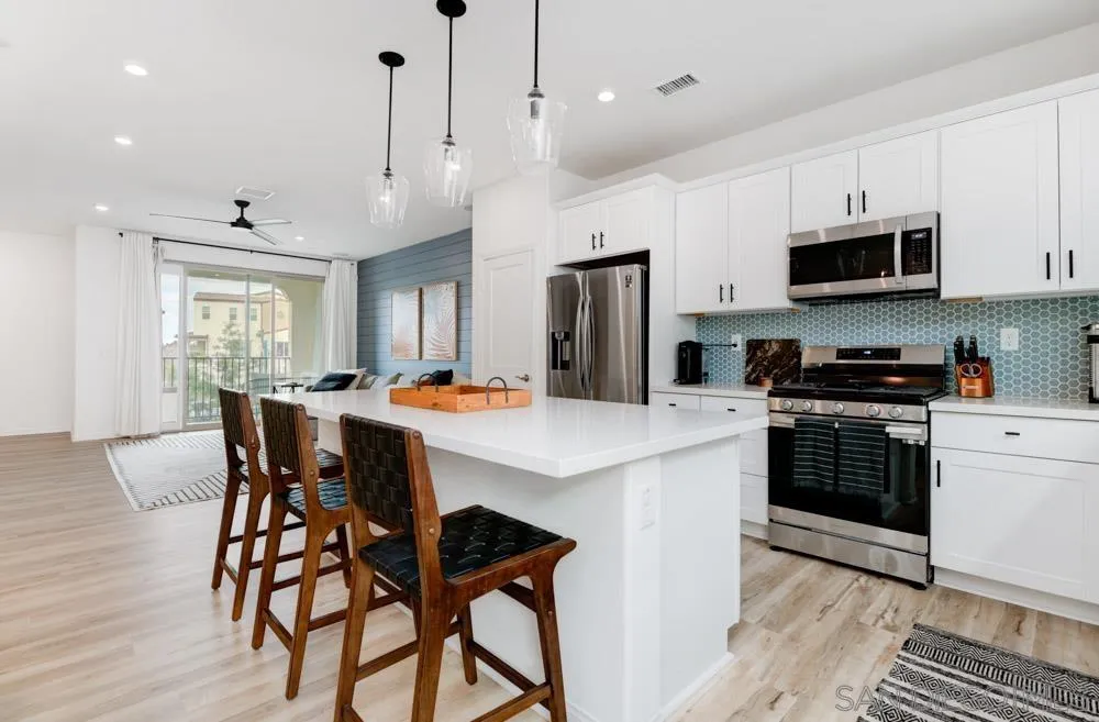 1643 Fig Tree Way Oceanside, CA 92056 - Photo 9 of 29 a kitchen with stainless steel appliances granite countertop a stove a refrigerator a microwave a sink a dining table and chairs with wooden floor