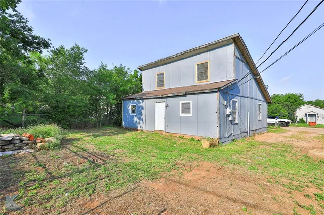 a front view of house with yard and trees in the background