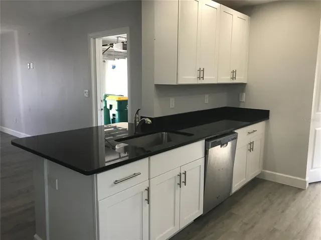 a kitchen with granite countertop white cabinets and a dishwasher