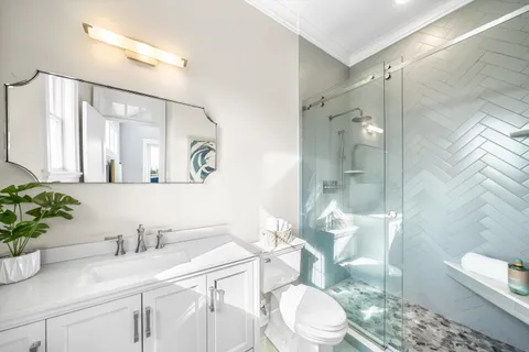 a bathroom with a granite countertop sink mirror a toilet and shower