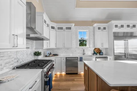 a kitchen with a stove a sink dishwasher and white cabinets with wooden floor