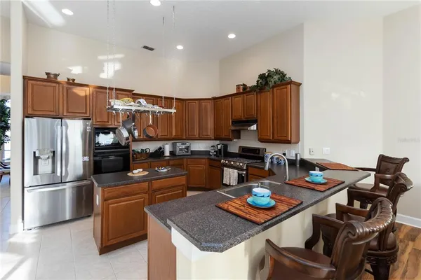 a kitchen with kitchen island granite countertop a sink a counter top space appliances and cabinets