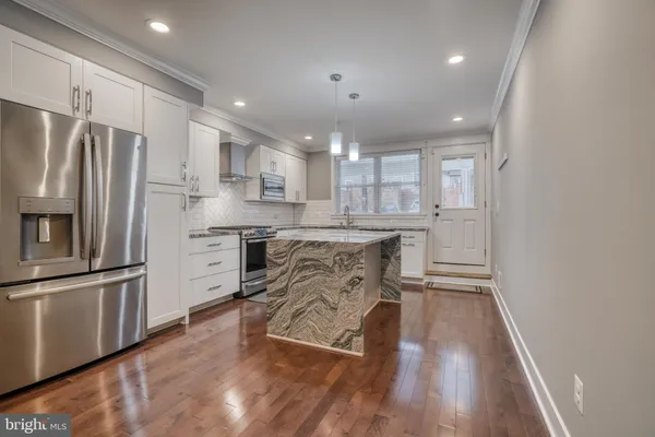 a kitchen with kitchen island white cabinets and stainless steel appliances