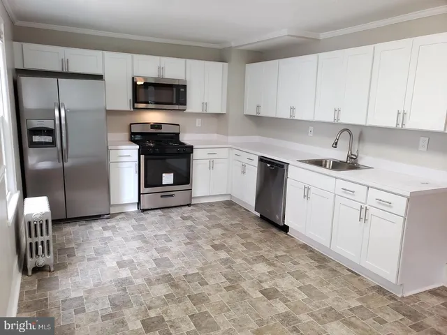 a kitchen with granite countertop a refrigerator and a stove top oven