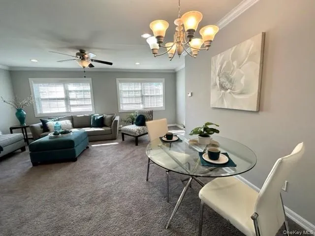 a living room with couches a chandelier and a dining room with wooden floor