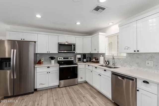 a kitchen with stainless steel appliances granite countertop white cabinets granite counter tops and a window