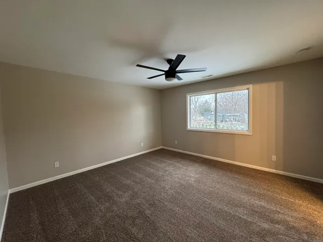 an empty room with ceiling fan and windows