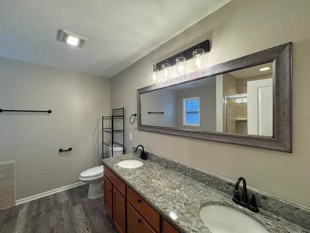 a bathroom with a granite countertop sink a toilet and a mirror