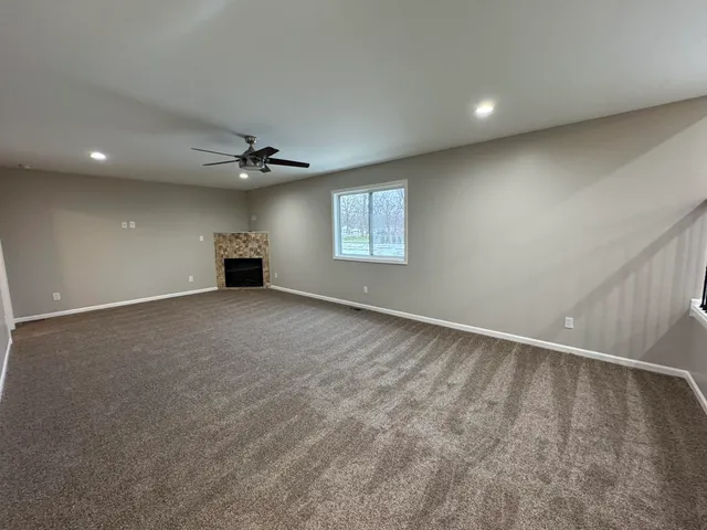 an empty room with a ceiling fan and windows