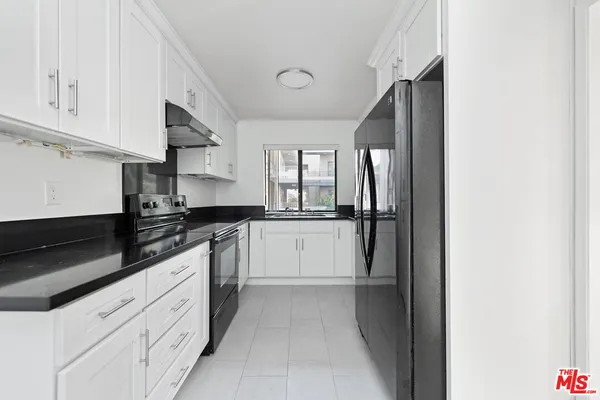 a kitchen with granite countertop white cabinets and stainless steel appliances