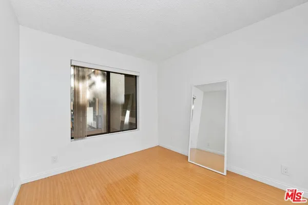 a view of an empty room with wooden floor and windows