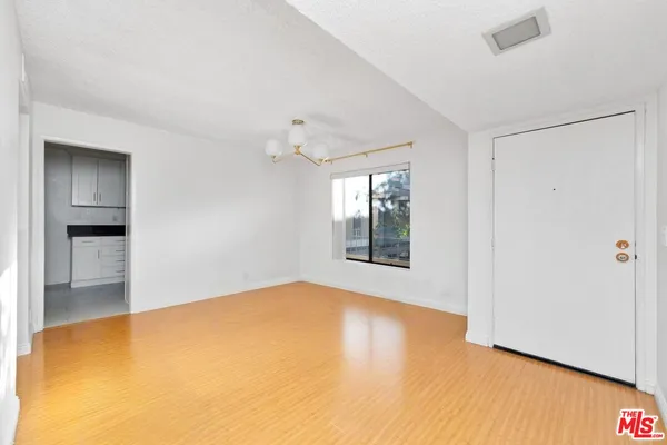 a view of an empty room with a window and wooden floor