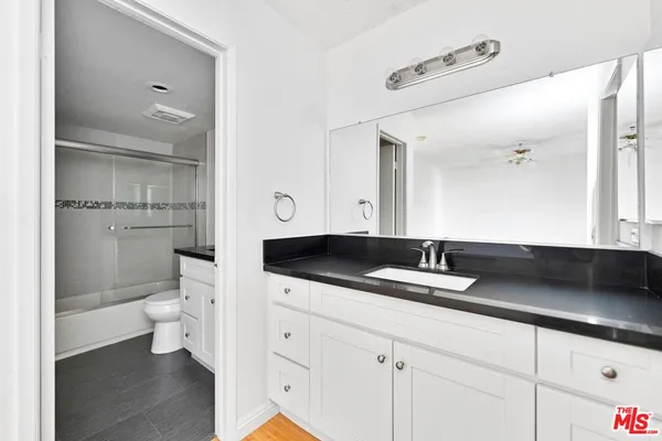 a bathroom with a granite countertop sink a toilet and a mirror