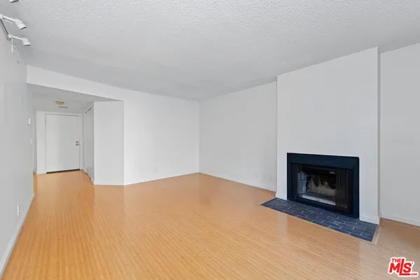 a view of an empty room with wooden floor and a fireplace