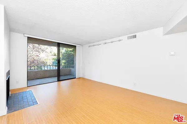 a view of empty room with wooden floor and fireplace