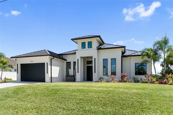 a kitchen with stainless steel appliances granite countertop a sink a stove a refrigerator and white cabinets with wooden floor