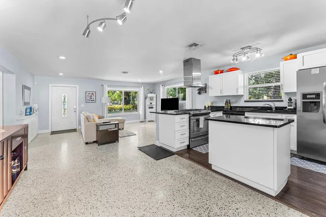 a kitchen with stainless steel appliances kitchen island granite countertop a stove a sink and a refrigerator