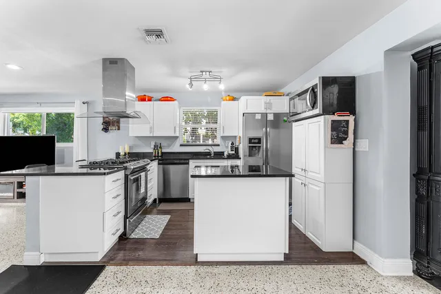 a kitchen with stainless steel appliances granite countertop a refrigerator a stove and a sink