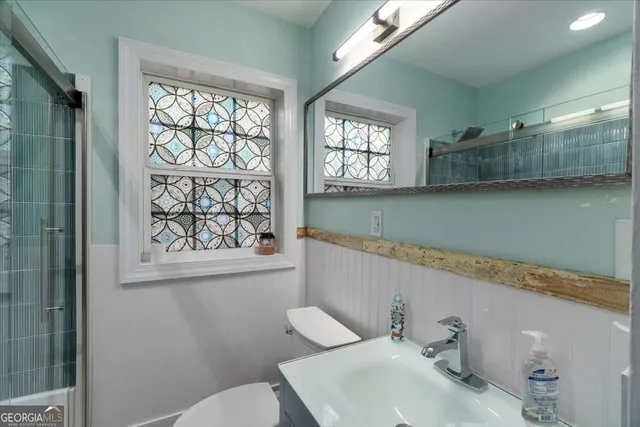 a bathroom with a sink mirror and a toilet
