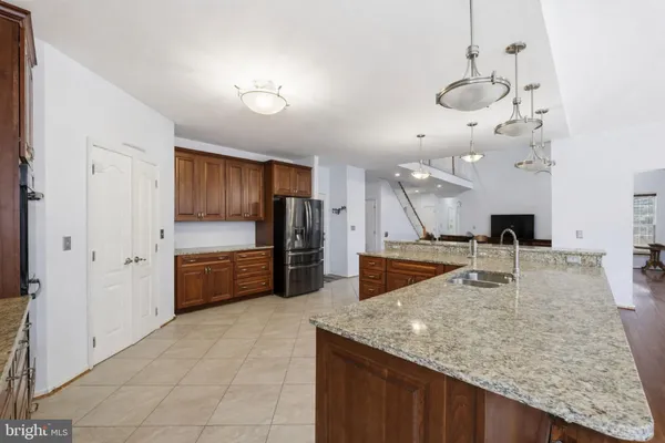 a large kitchen with kitchen island a large counter top stainless steel appliances and cabinets