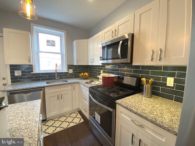 a kitchen with granite countertop a sink stove and microwave