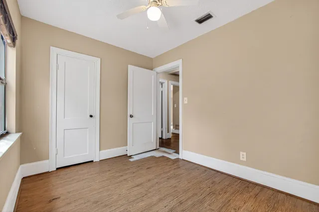 an empty room with wooden floor and ceiling fan