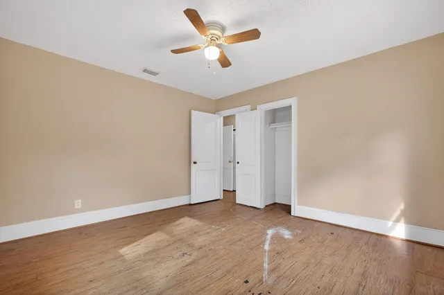 an empty room with wooden floor and ceiling fan