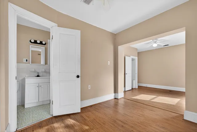 a view of an empty room with a window and wooden floor
