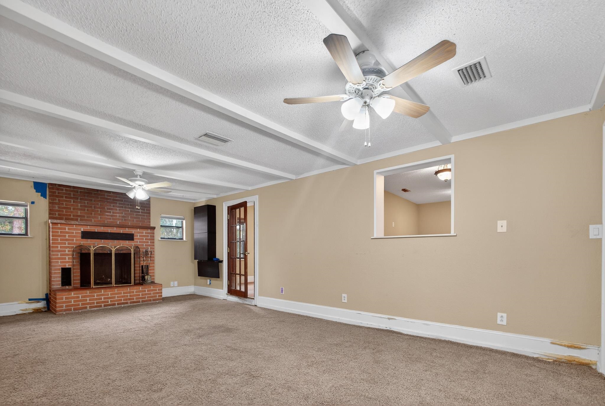 2907 North 5th Street St. Augustine, FL 32084 - Photo 39 of 71 Unfurnished living room featuring a fireplace, beam ceiling, a ceiling fan, a textured ceiling, and carpet floors