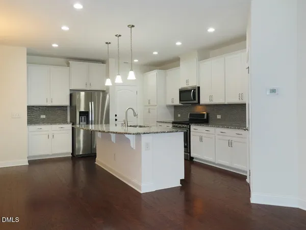 a large kitchen with stainless steel appliances granite countertop a stove a sink a refrigerator and a microwave