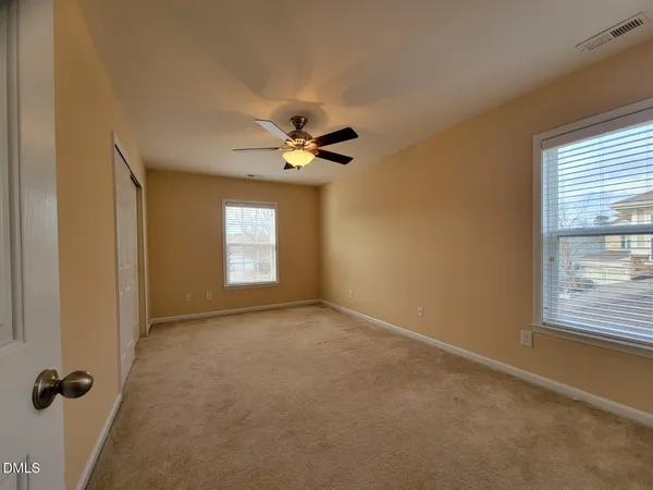 an empty room with windows and fan