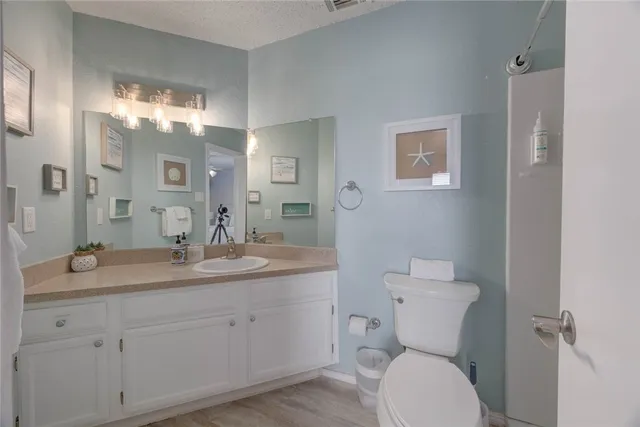 a bathroom with a granite countertop toilet a sink and mirror