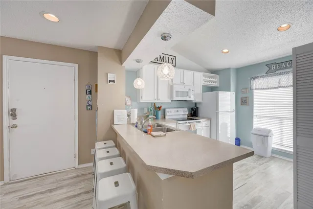 a kitchen with stainless steel appliances a refrigerator a sink dishwasher and white cabinets with wooden floor