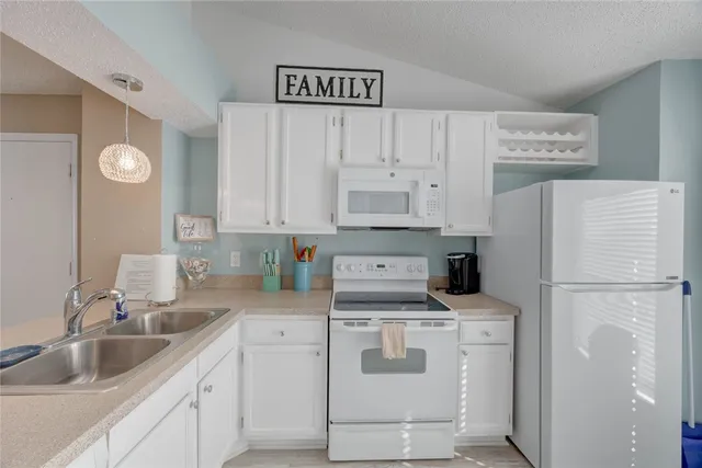 a view of kitchen with refrigerator and white cabinets