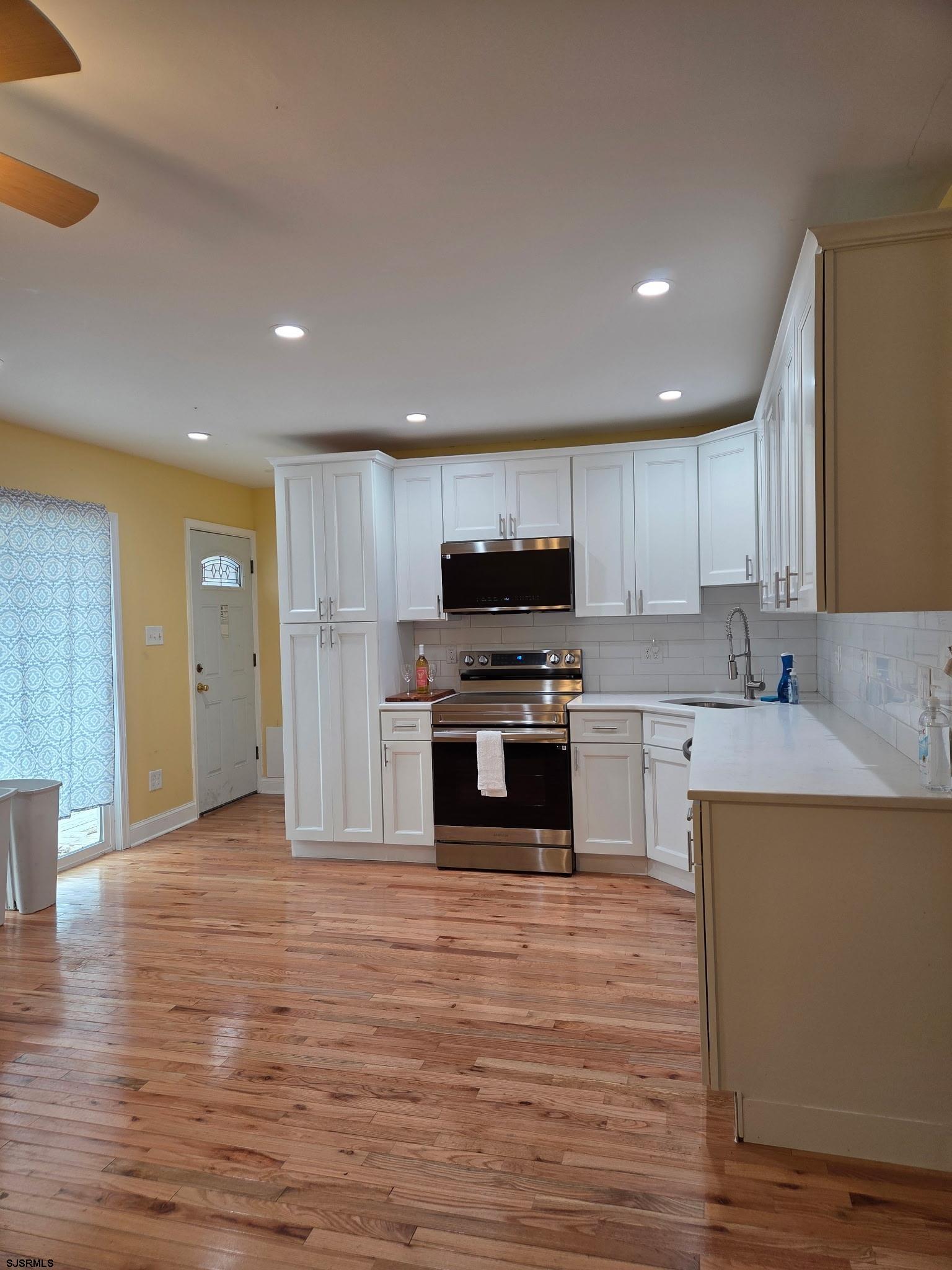 131 Jones Kane Road Williamstown, NJ 08094 - Photo 4 of 18 a kitchen with wooden floors and white stainless steel appliances