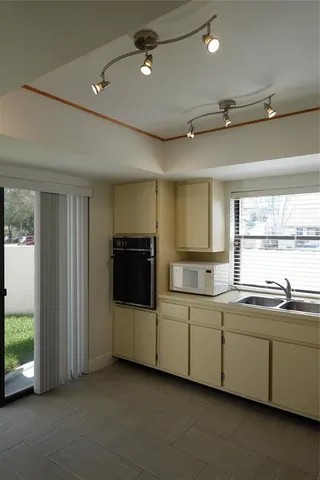 a utility room with stainless steel appliances wooden floor and view of living room