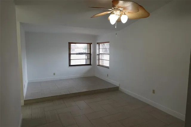 an empty room with windows and chandelier fan