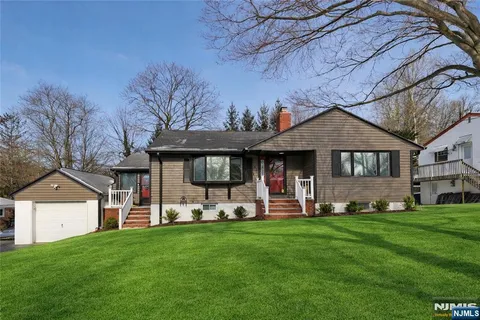 a front view of a house with a garden and trees