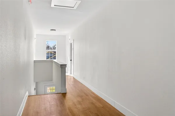a view of an empty room with wooden floor and a ceiling fan