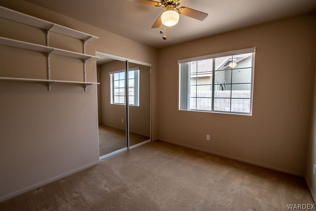 4213 East Cane Ranch Road Kingman, AZ 86401 - Photo 16 of 40 an empty room with a chandelier fan and windows