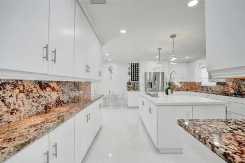 a kitchen with granite countertop white cabinets and a window