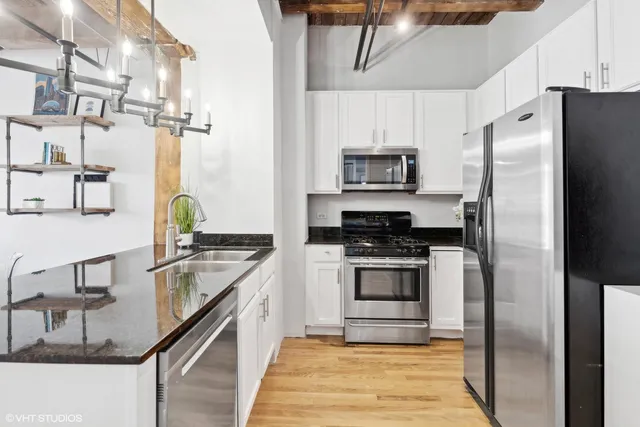 a kitchen with stainless steel appliances granite countertop a refrigerator a stove and a sink