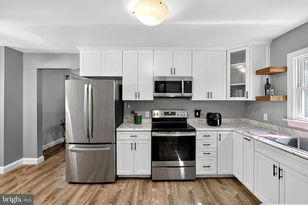 a kitchen with cabinets stainless steel appliances and wooden floor
