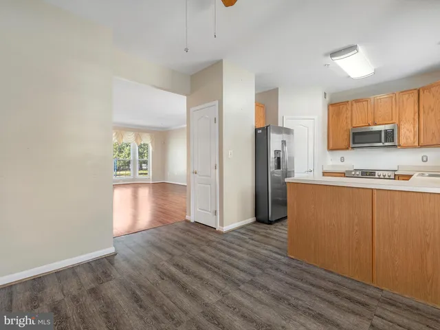 a view of kitchen with stainless steel appliances wooden floor and a window