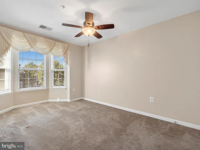 an empty room with a window and a fan