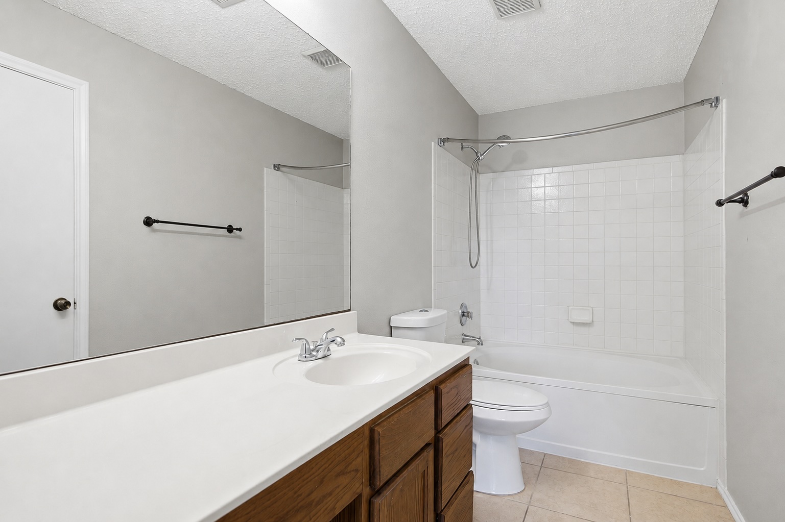 7900 Rosenberry Drive Austin, TX 78747 - Photo 20 of 27 A pristine bath features a wood vanity, an integrated sink, and ample counter space alongside a clean tiled tub-shower.
