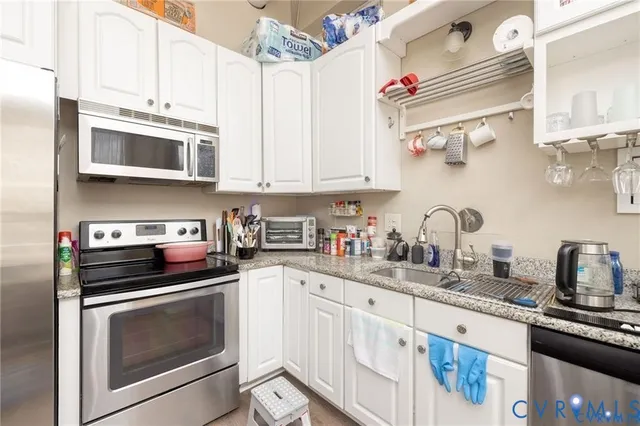 a kitchen with stainless steel appliances kitchen island granite countertop a stove top oven a sink and a dining table with wooden floor