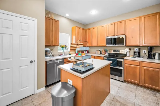 a kitchen with stainless steel appliances granite countertop a stove a sink dishwasher a microwave oven and a refrigerator with wooden floor