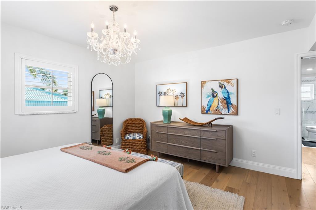 940 3rd Street South, Unit 201 Naples, FL 34102 - Photo 11 of 27 a bedroom with a bed and a chandelier