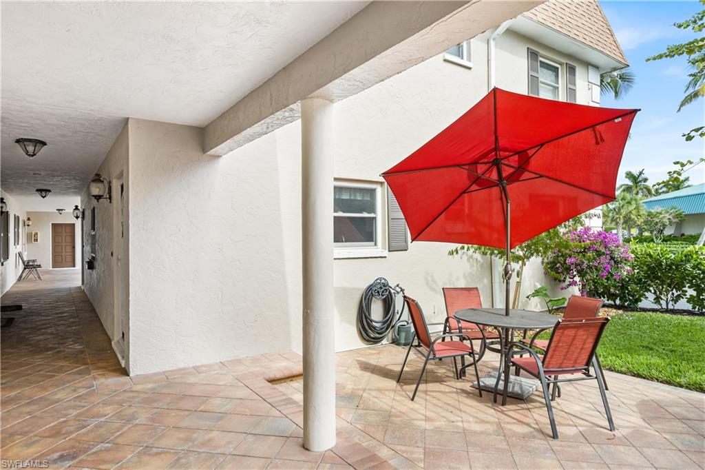 940 3rd Street South, Unit 201 Naples, FL 34102 - Photo 20 of 27 a patio with a table and chairs under an umbrella